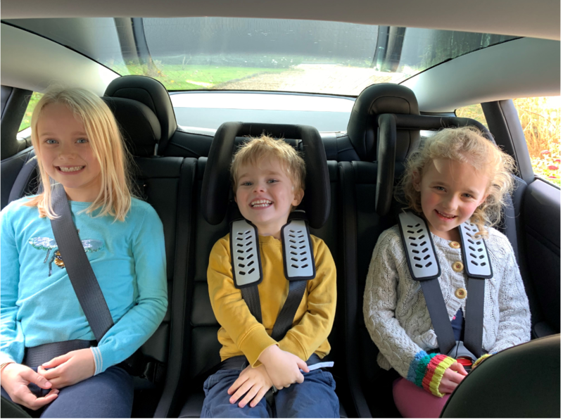 3 children in the back of a Tesla